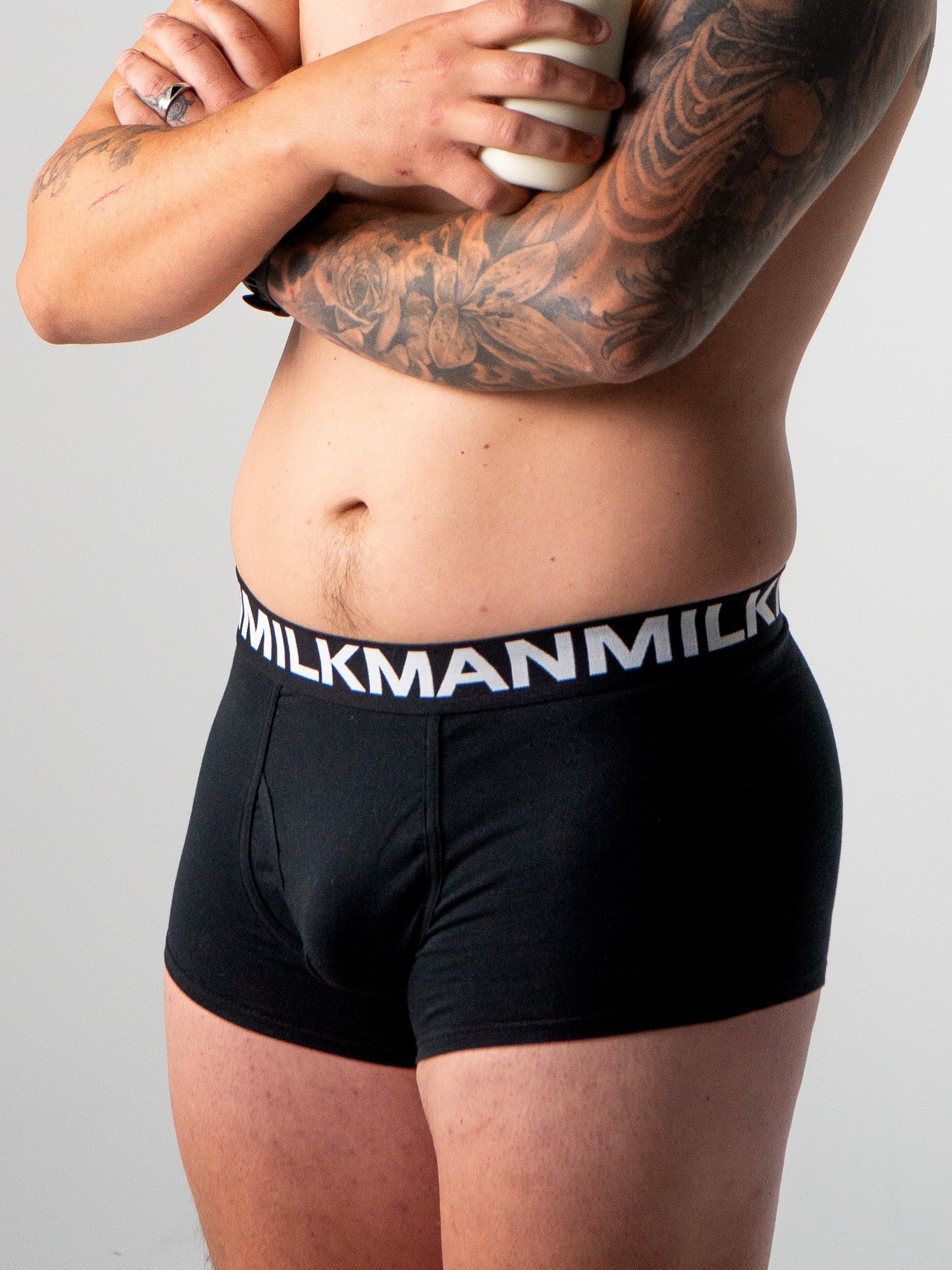 Person wearing black underwear with 'Milkman' waistband on a gray background